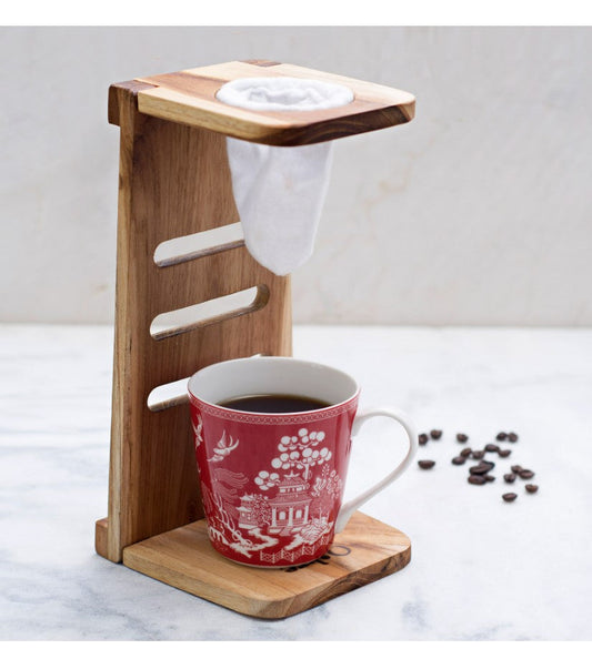  A handcrafted wooden Costa Rican chorreador with cotton cloth filter brewing coffee on a kitchen counter, gift-wrapped nearby.