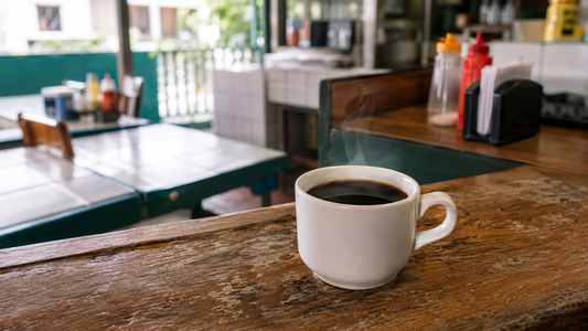 Small white cup of black coffee served on a wooden counter at a Costa Rican soda
